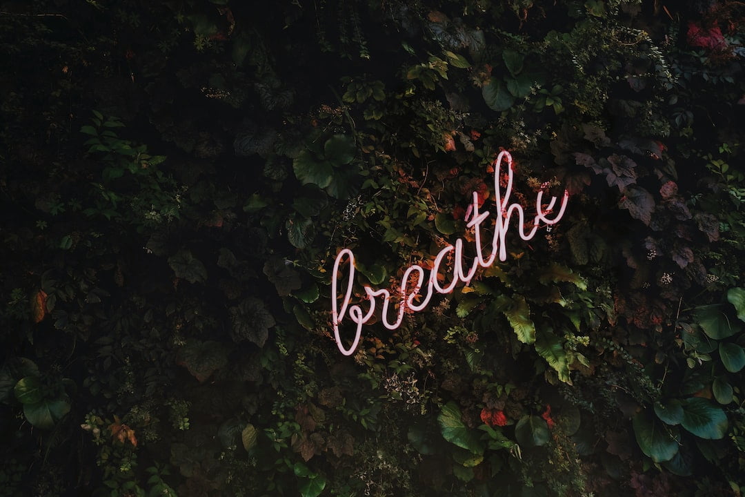 A neon sign with the word breathe in front of a green wall.