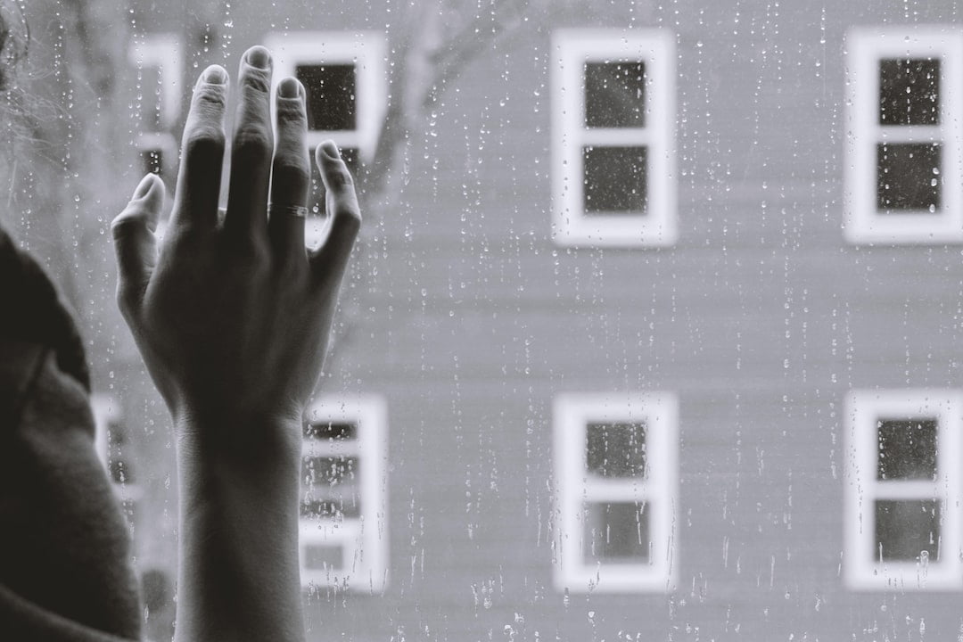 A black and white photo of a hand reaching out of a window.