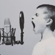 A boy is yelling into a microphone.