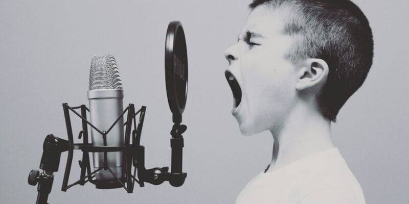 A boy is yelling into a microphone.