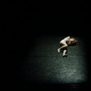 A woman laying on the floor in the dark.