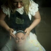 A woman in an apron is getting a steam treatment.