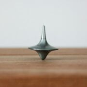 A metal spinning top on a wood surface.