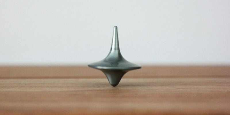 A metal spinning top on a wood surface.