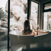 A woman is sitting in a tub looking out at the rocks.