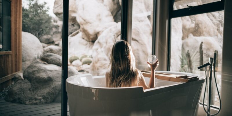 A woman is sitting in a tub looking out at the rocks.