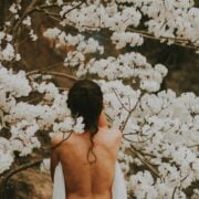 A woman standing under a tree with white flowers.