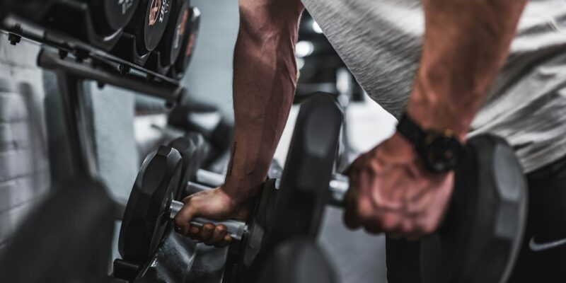 A man lifting dumbbells in a gym.