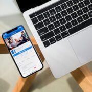 A laptop with a phone on it next to a wooden table.