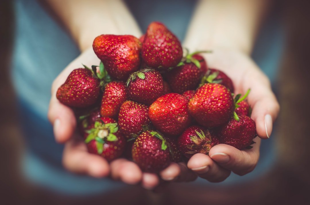 A person holding a pile of strawberries.