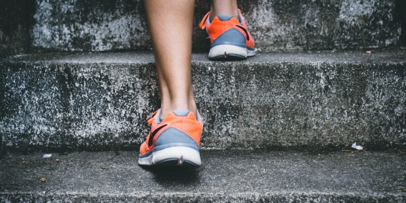 A person's legs and shoes on a concrete staircase.