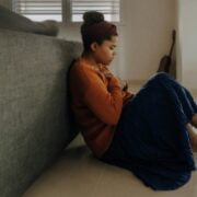 A woman sitting on the floor in front of a couch.