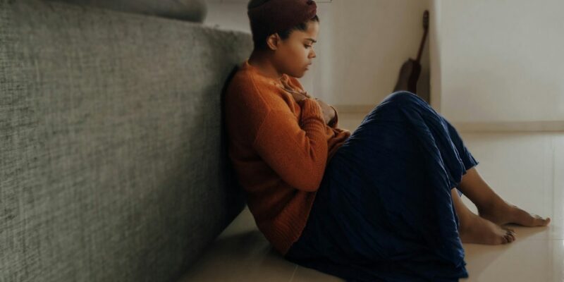 A woman sitting on the floor in front of a couch.