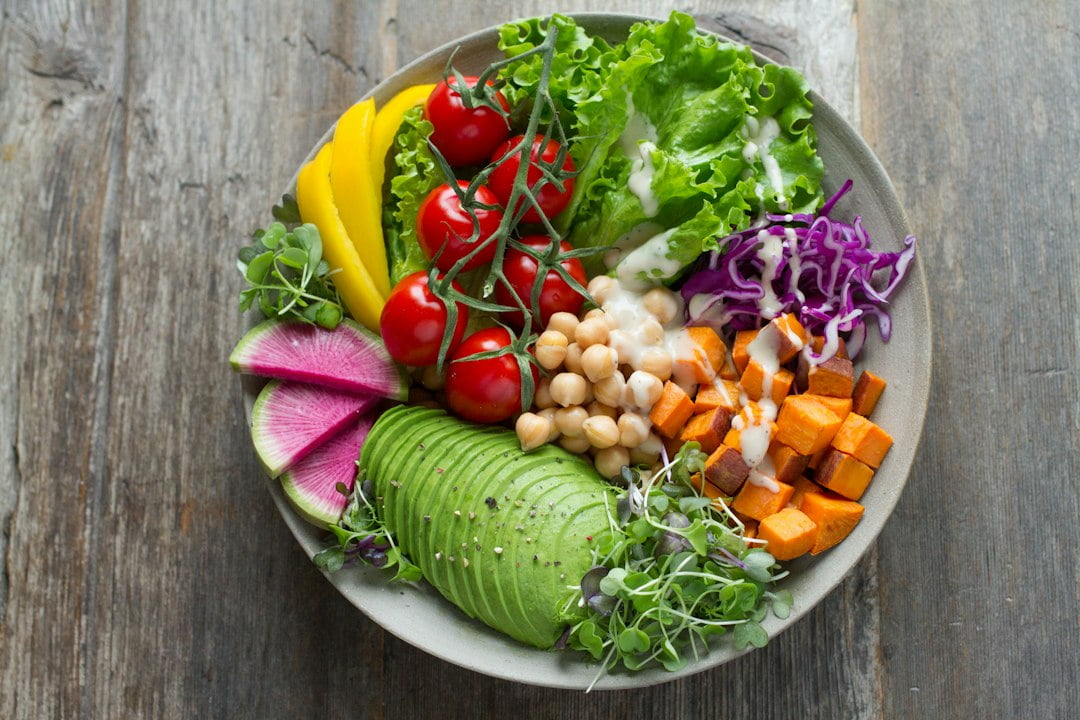 A bowl full of vegetables and fruits on a wooden table.