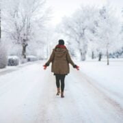 A woman walking down a snow covered road.