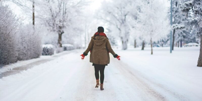 A woman walking down a snow covered road.