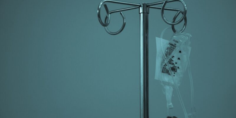 An iv bag on a stand against a blue background.