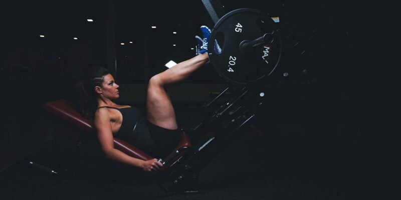 A woman doing a squat on a machine.