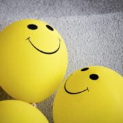 Three yellow balloons with smiley faces on them.