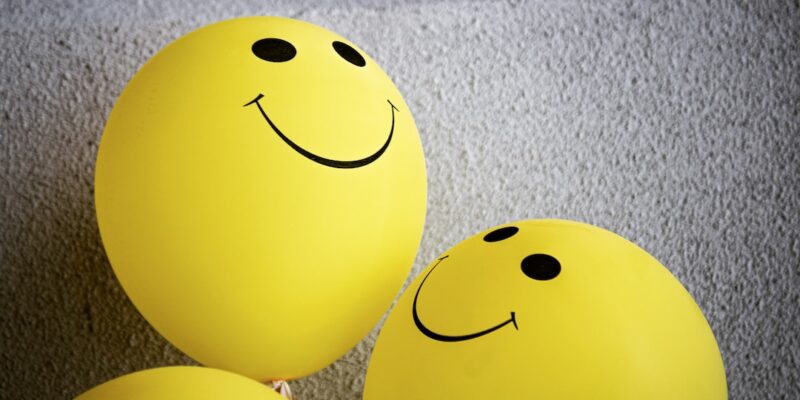 Three yellow balloons with smiley faces on them.