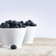 A couple of white bowls filled with blueberries.