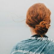 A woman with red hair looking out over the ocean.