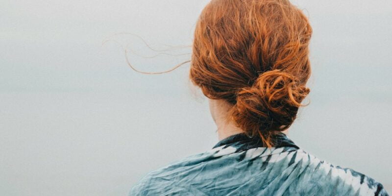 A woman with red hair looking out over the ocean.