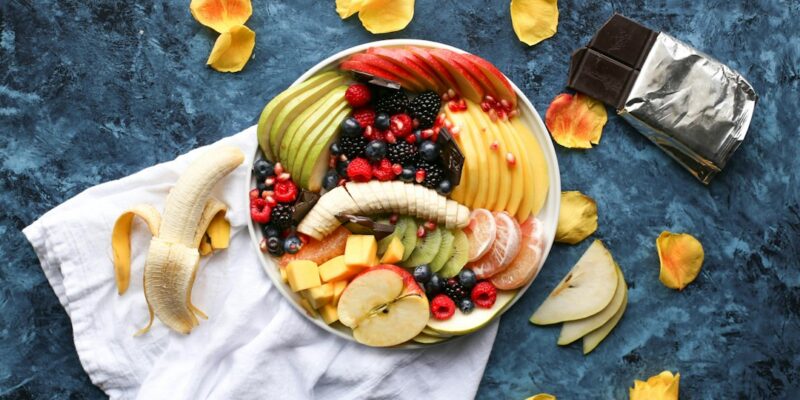 A plate of fruit and chocolate on a blue background.