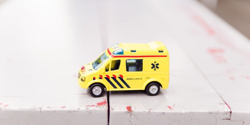 A yellow toy ambulance on a white surface.