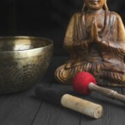 A buddha statue and a singing bowl on a wooden table.