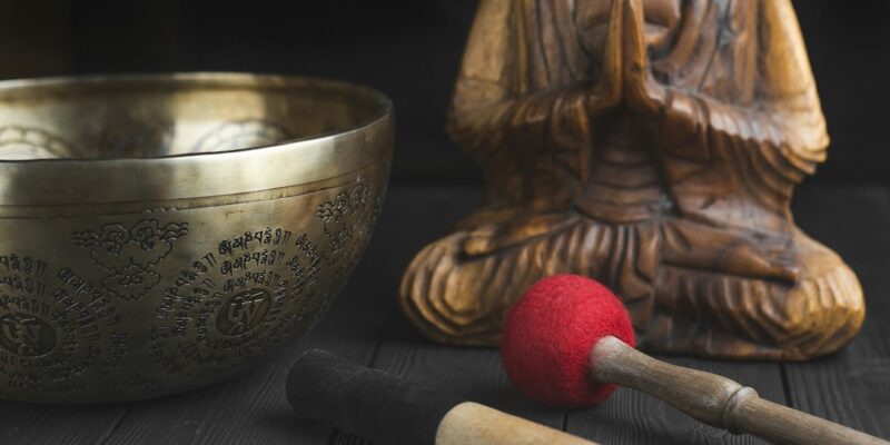 A buddha statue and a singing bowl on a wooden table.