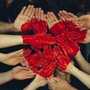 A group of people with red painted hands in a circle.