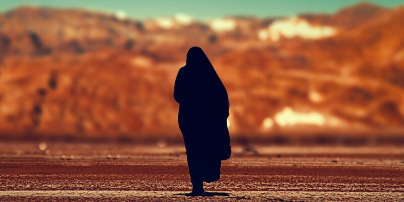 A silhouette of a woman walking in the desert.