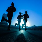 Silhouettes of people running on a road at sunset.