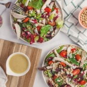 Two plates of salad with a fork and a knife.