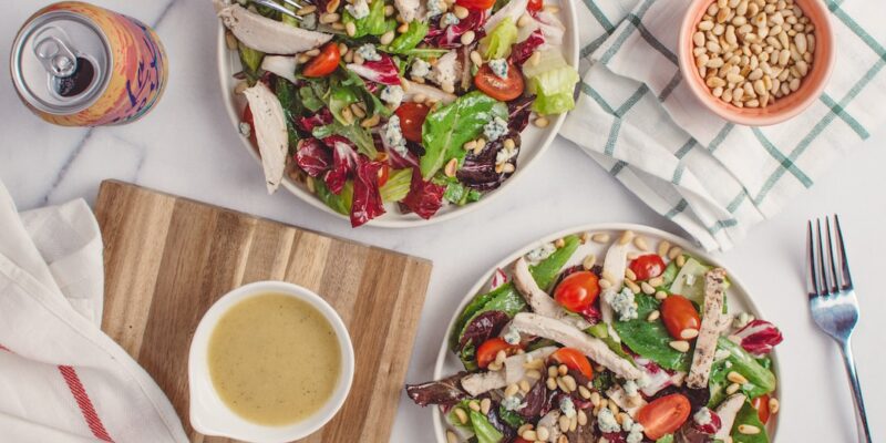 Two plates of salad with a fork and a knife.