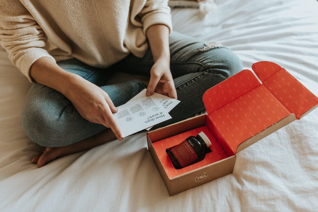 A woman is sitting on a bed with a box in front of her.