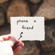 A person holding up a piece of paper that says phone a friend.