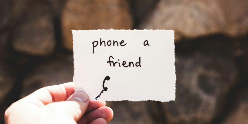 A person holding up a piece of paper that says phone a friend.