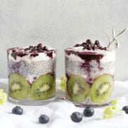 Two glasses of fruit and yogurt with blueberries.