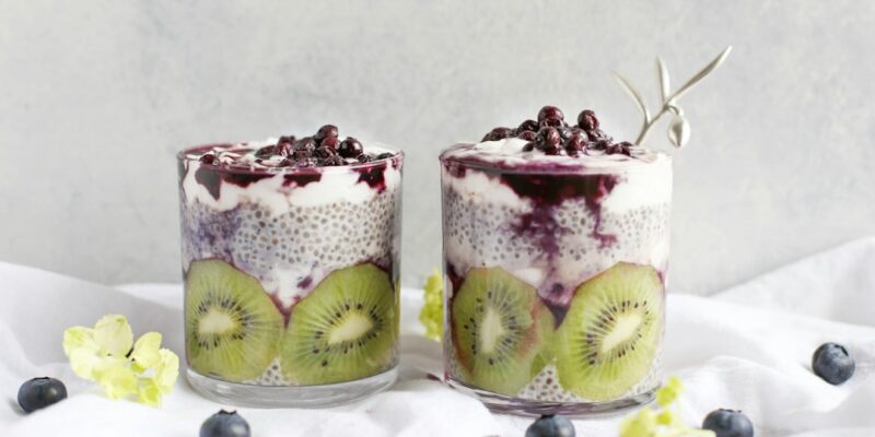 Two glasses of fruit and yogurt with blueberries.