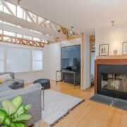 A living room with a fireplace and wooden beams.