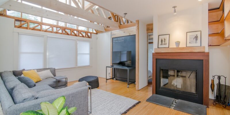 A living room with a fireplace and wooden beams.