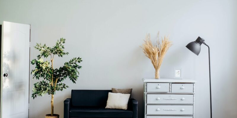 An empty room with a black couch and a lamp.