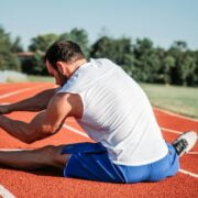 A man stretching on a running track.