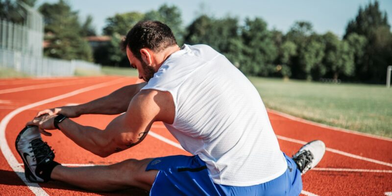 A man stretching on a running track.