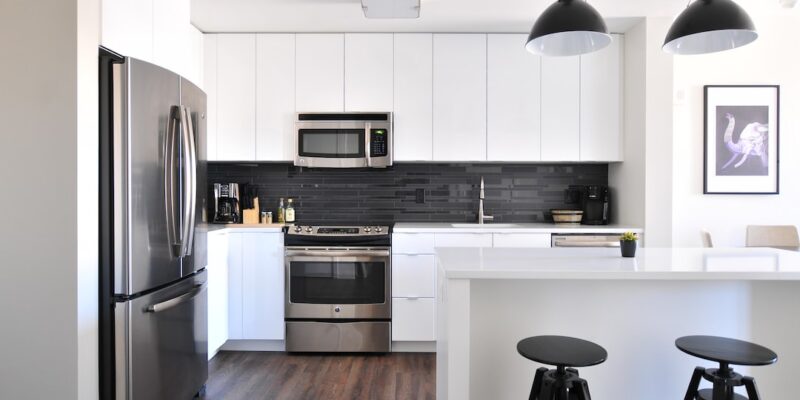 A kitchen with white cabinets and black countertops.