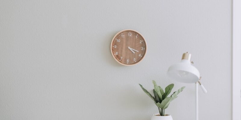 A white desk with a clock on it.