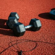 A pair of dumbbells on a red track.