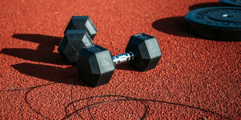 A pair of dumbbells on a red track.